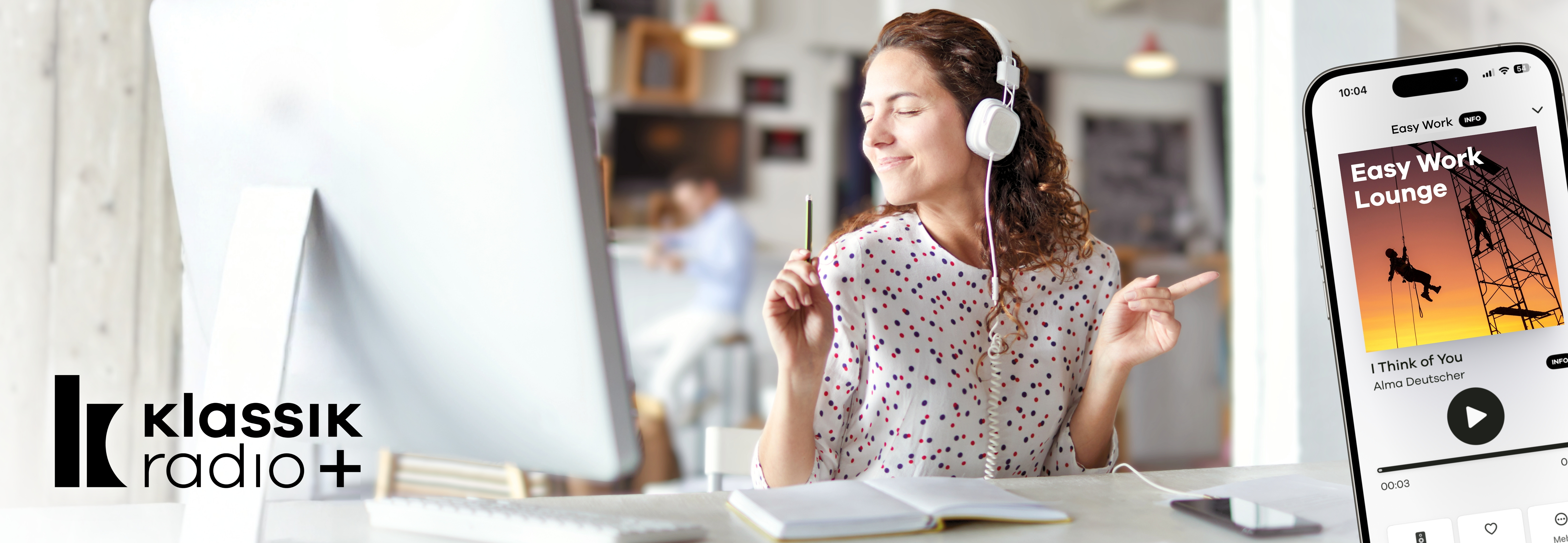 Mitarbeiterin sitzt am Schreibtisch in einem Unternehmen und hört Musik 