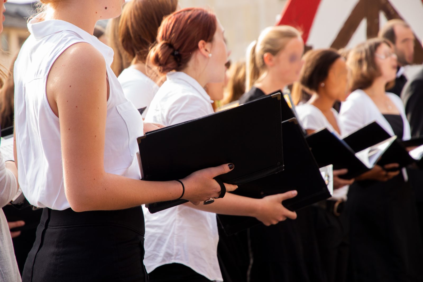 Chormitglieder singen sich ein, mit Gesangsmappen in der Hand  |  Chormitglieder singen sich ein, mit Gesangsmappen in der Hand 