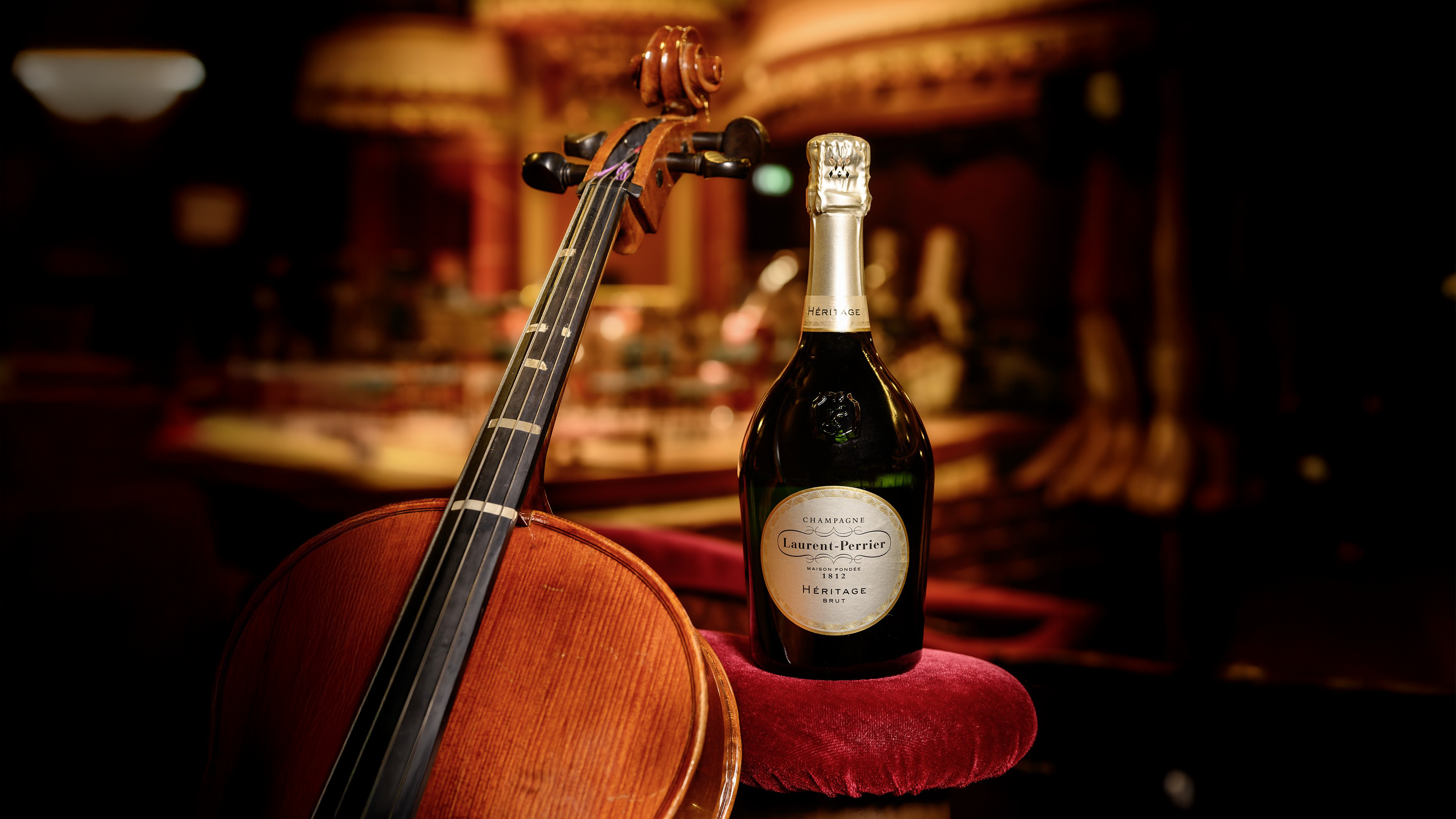 Zwei gefüllte Champagnergläser und eine Flasche Laurent-Perrier vor elegantem Hintergrund