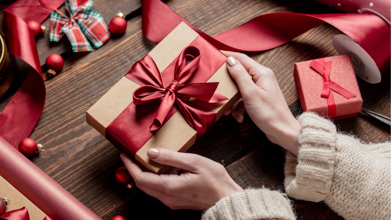 Geschenk mit Schleife in den Händen einer Frau