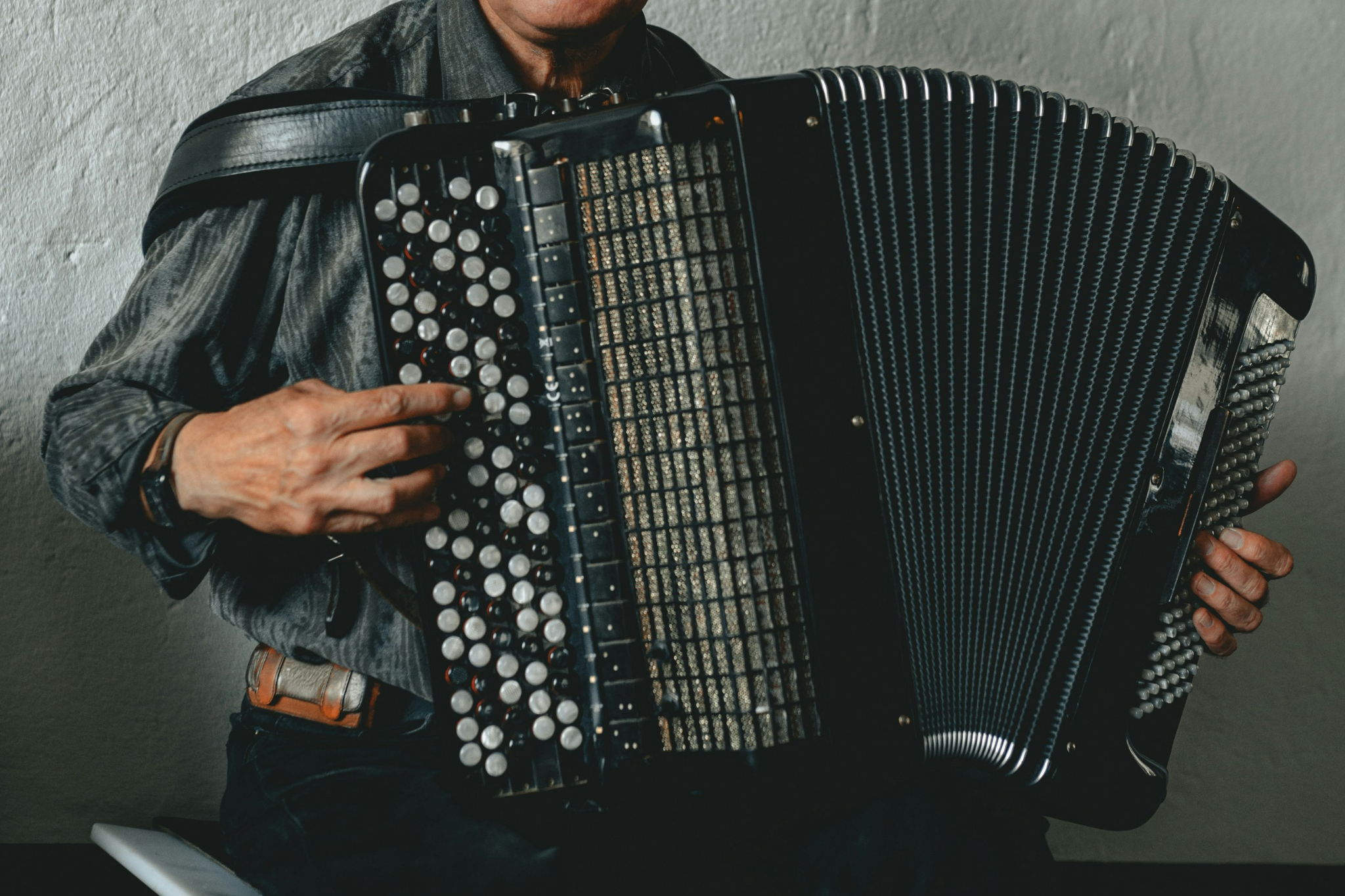 Person spielt ein großes schwarzes Akkordeon, Hände auf den Knöpfen und Tasten