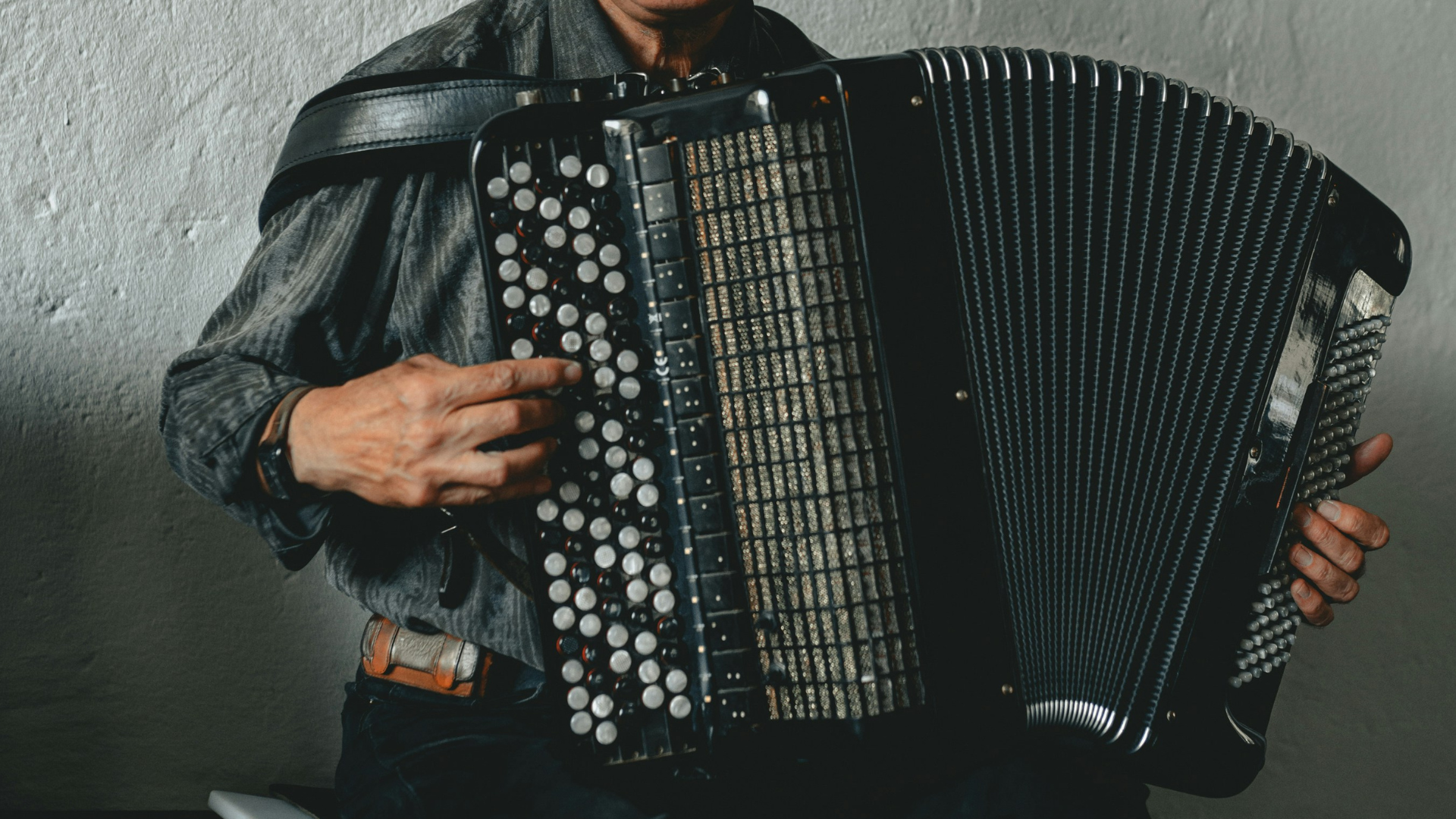Person spielt ein großes schwarzes Akkordeon, Hände auf den Knöpfen und Tasten
