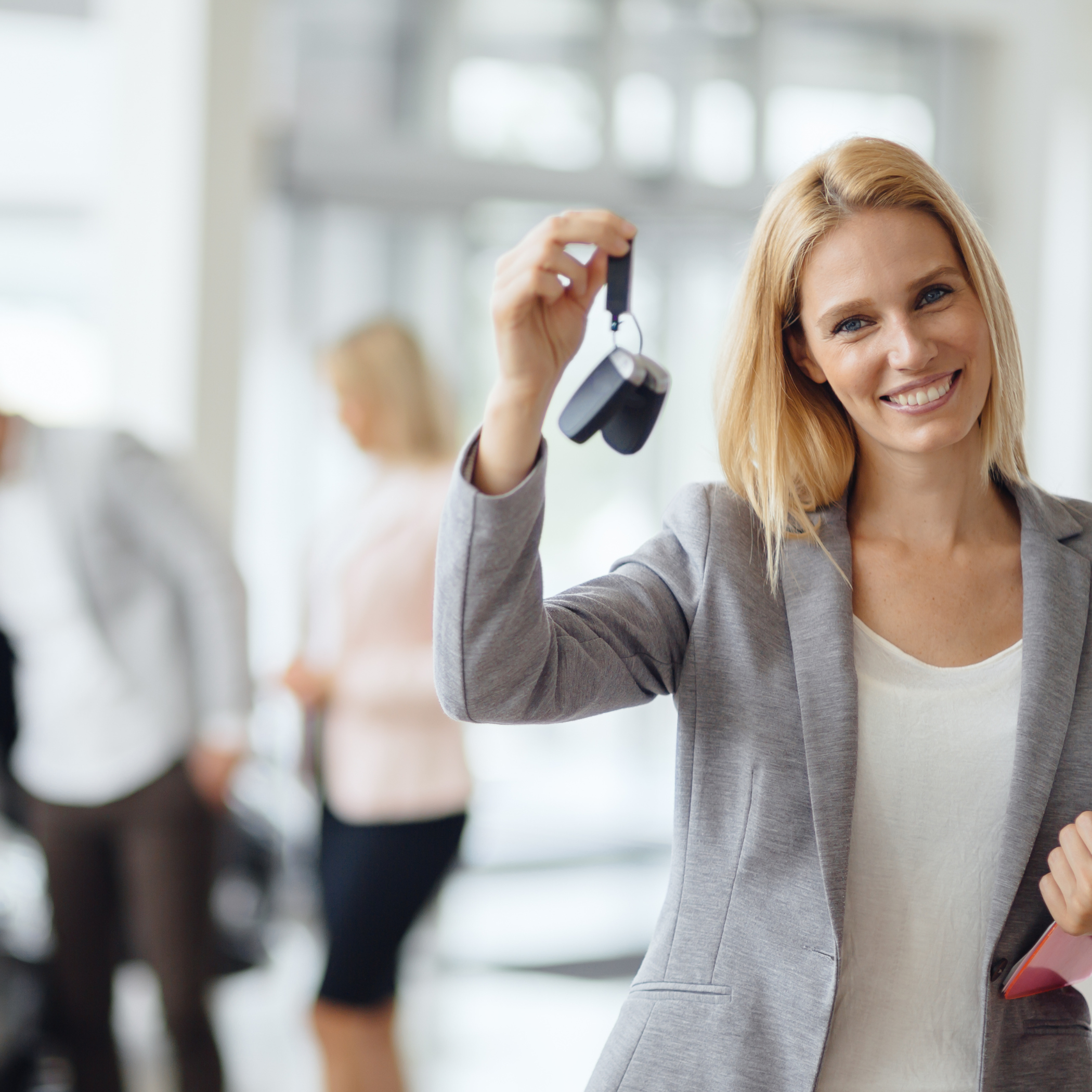 Frau im Autohaus mit Autoschlüssel