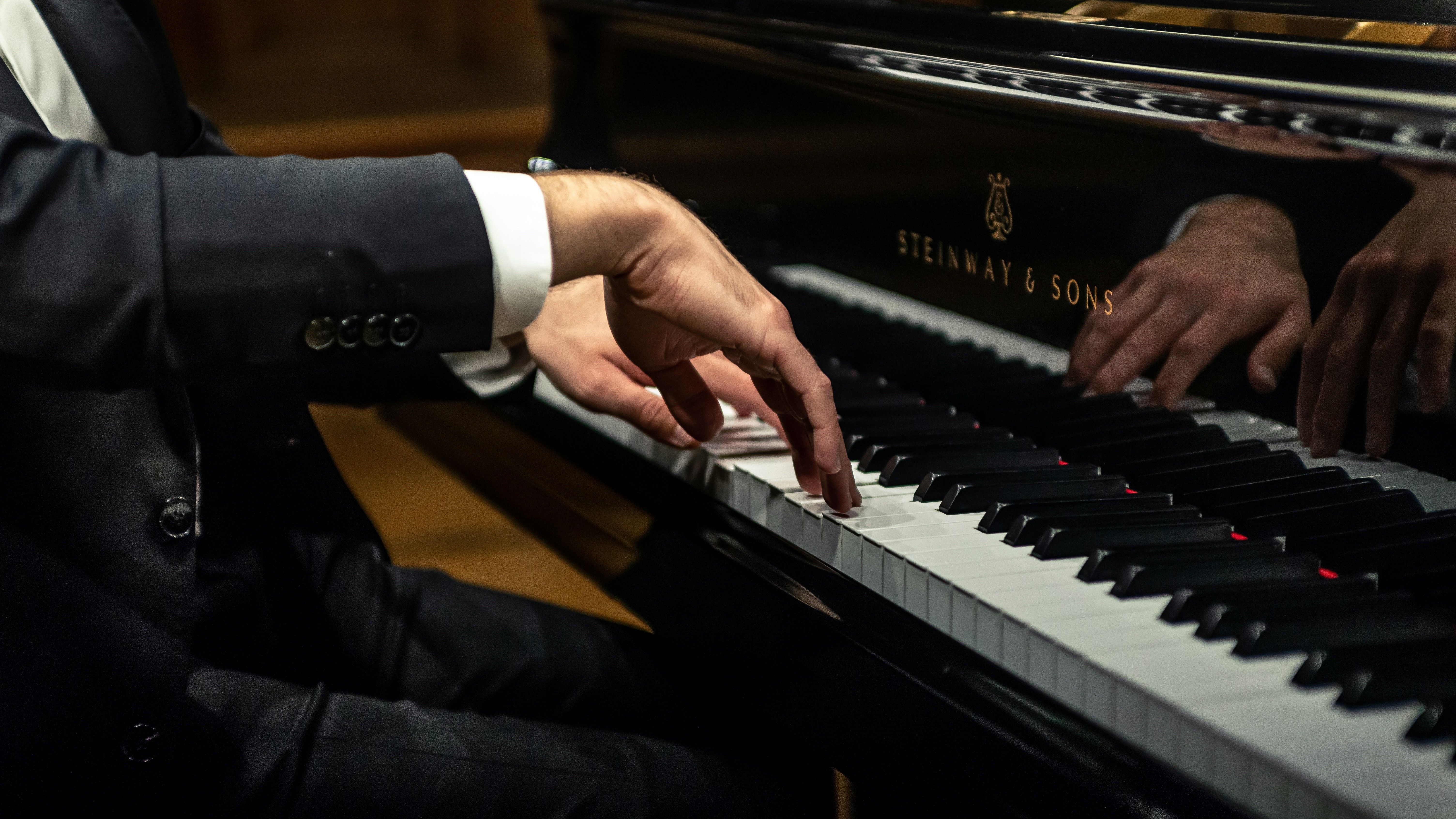 Man spielt im schwarzen Anzug Piano