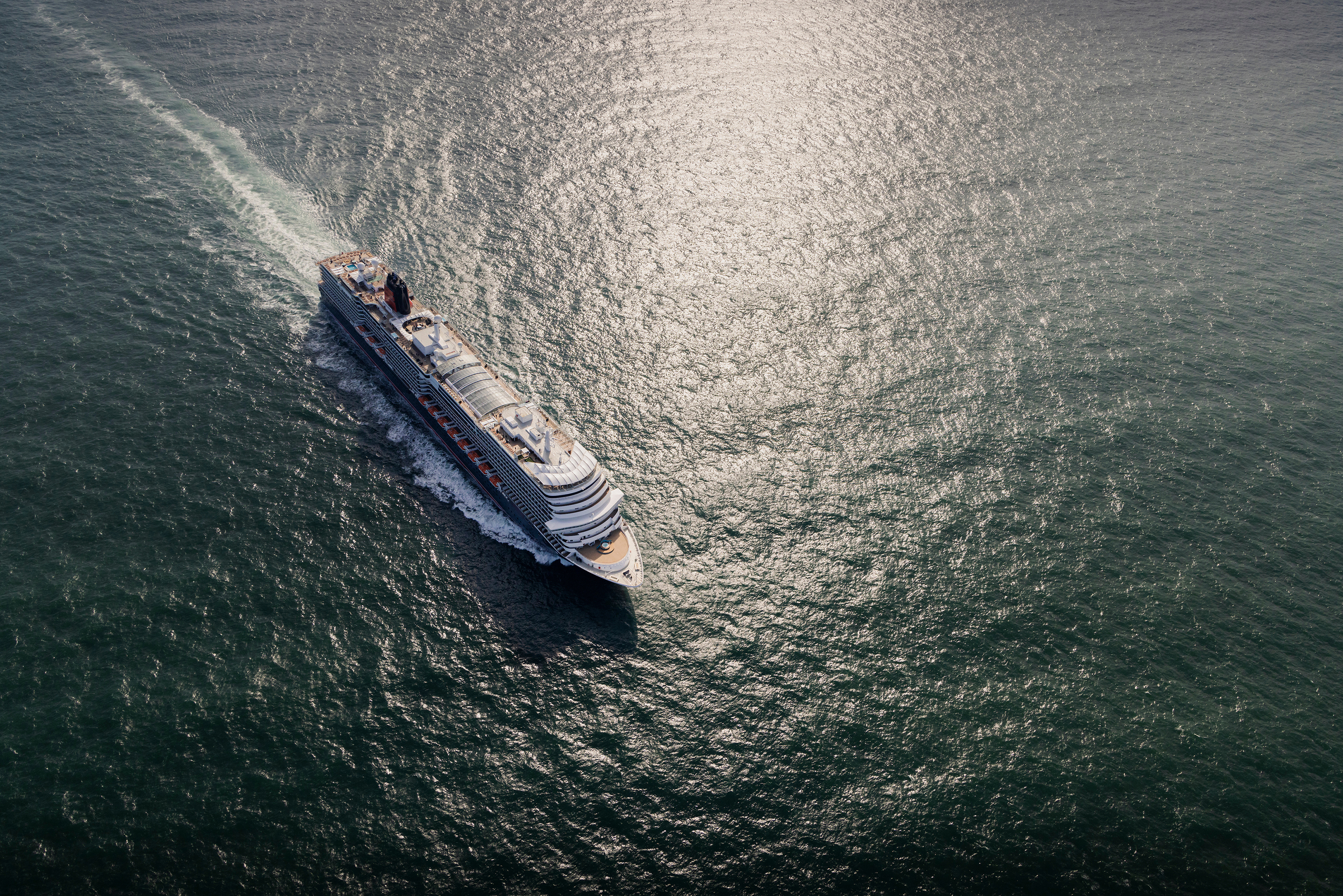 Kreuzfahrtschiff fährt bei Sonnenlicht über das offene Meer