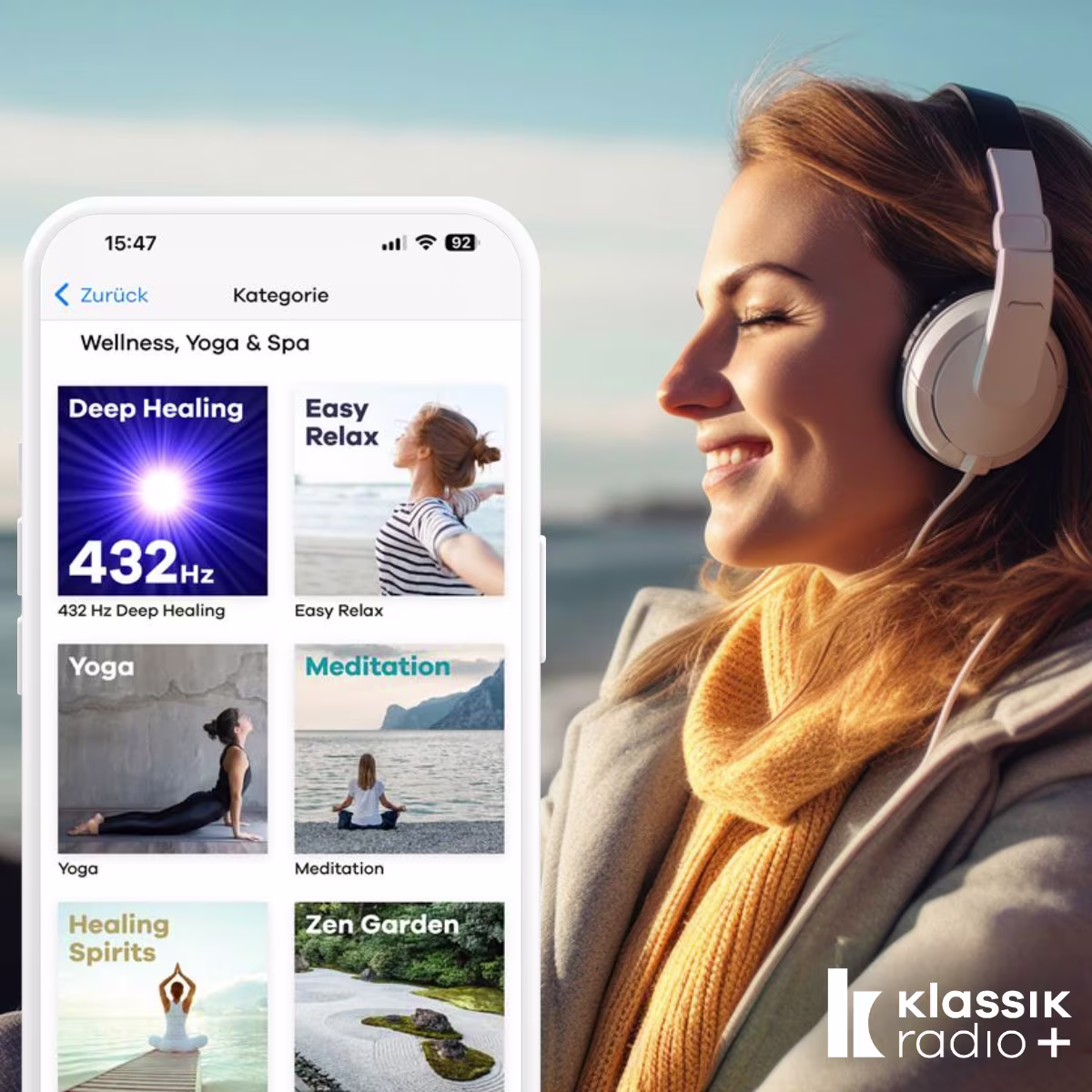 Frau am Strand in Winterkleidung hört Musik in weißen Kopfhörern. Im Vordergrund ist ein Handy mit der offenen Klassik Radio Plus App.