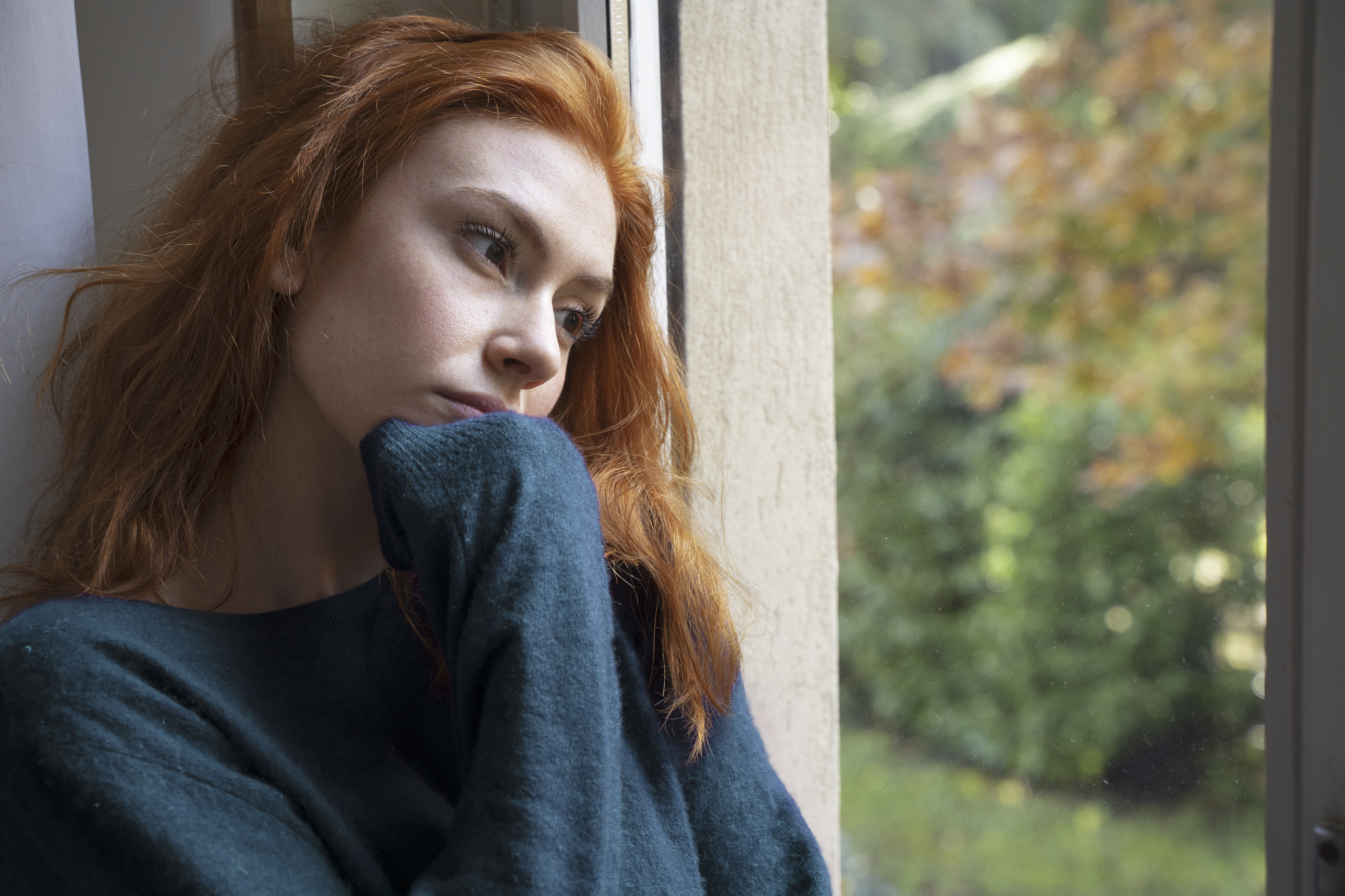 my7steps Nachdenkliche Frau mit roten Haaren am Fenster