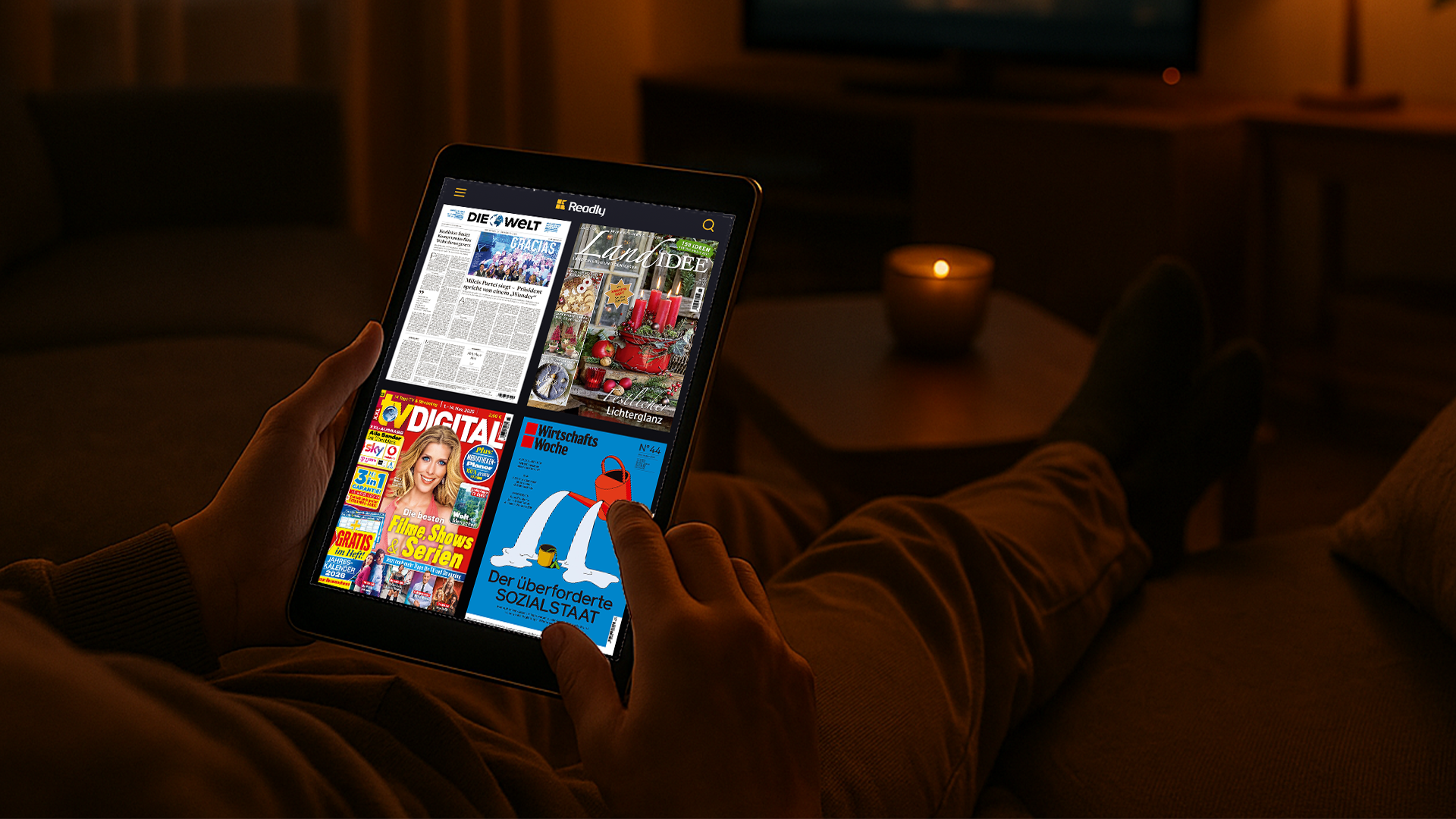 Person liest digitale Zeitschriften auf einem Tablet im gemütlich beleuchteten Wohnzimmer