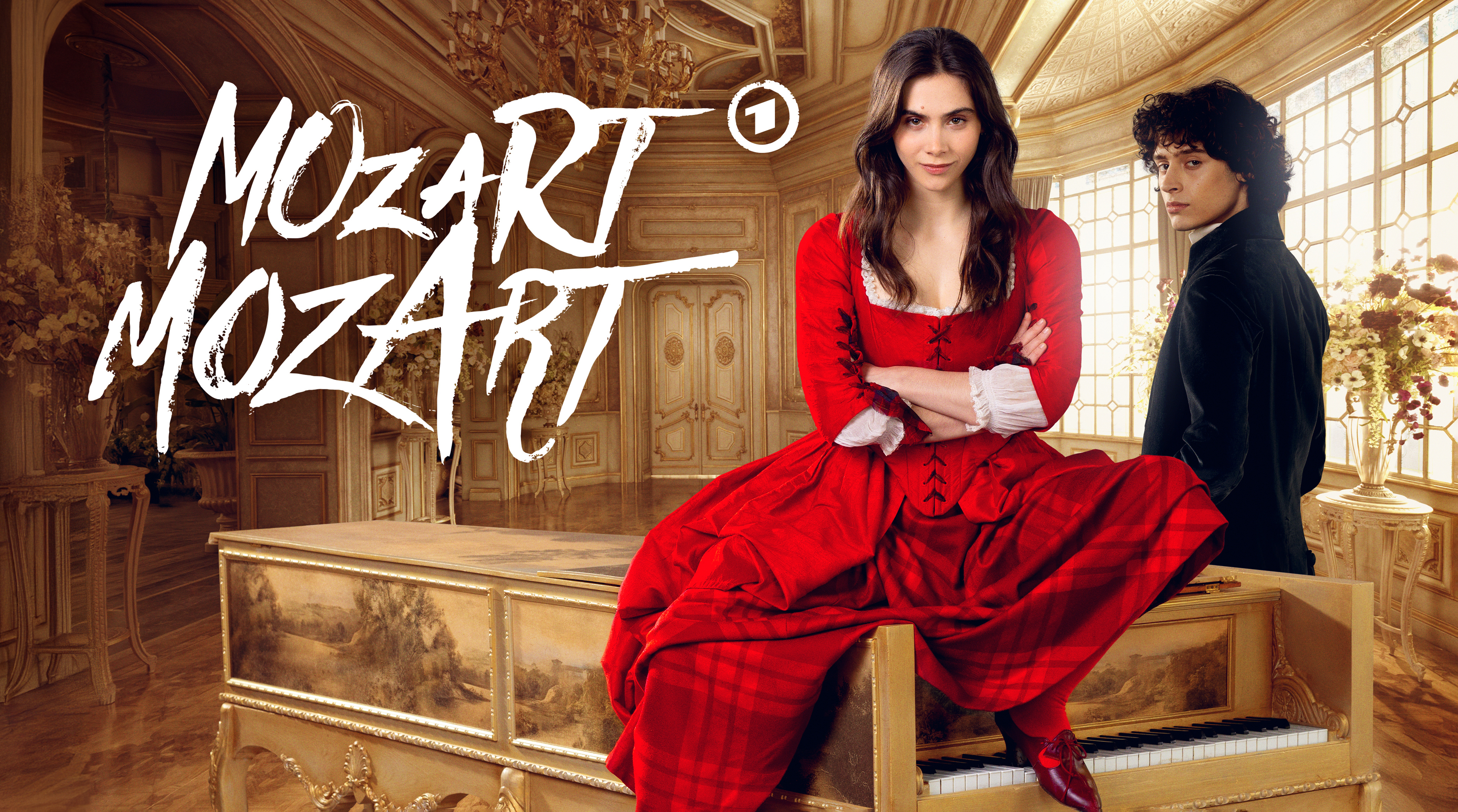 Frau im roten Kleid sitzt auf einem goldenen Flügel in prunkvollem Saal, Schriftzug "Mozart" im Hintergrund