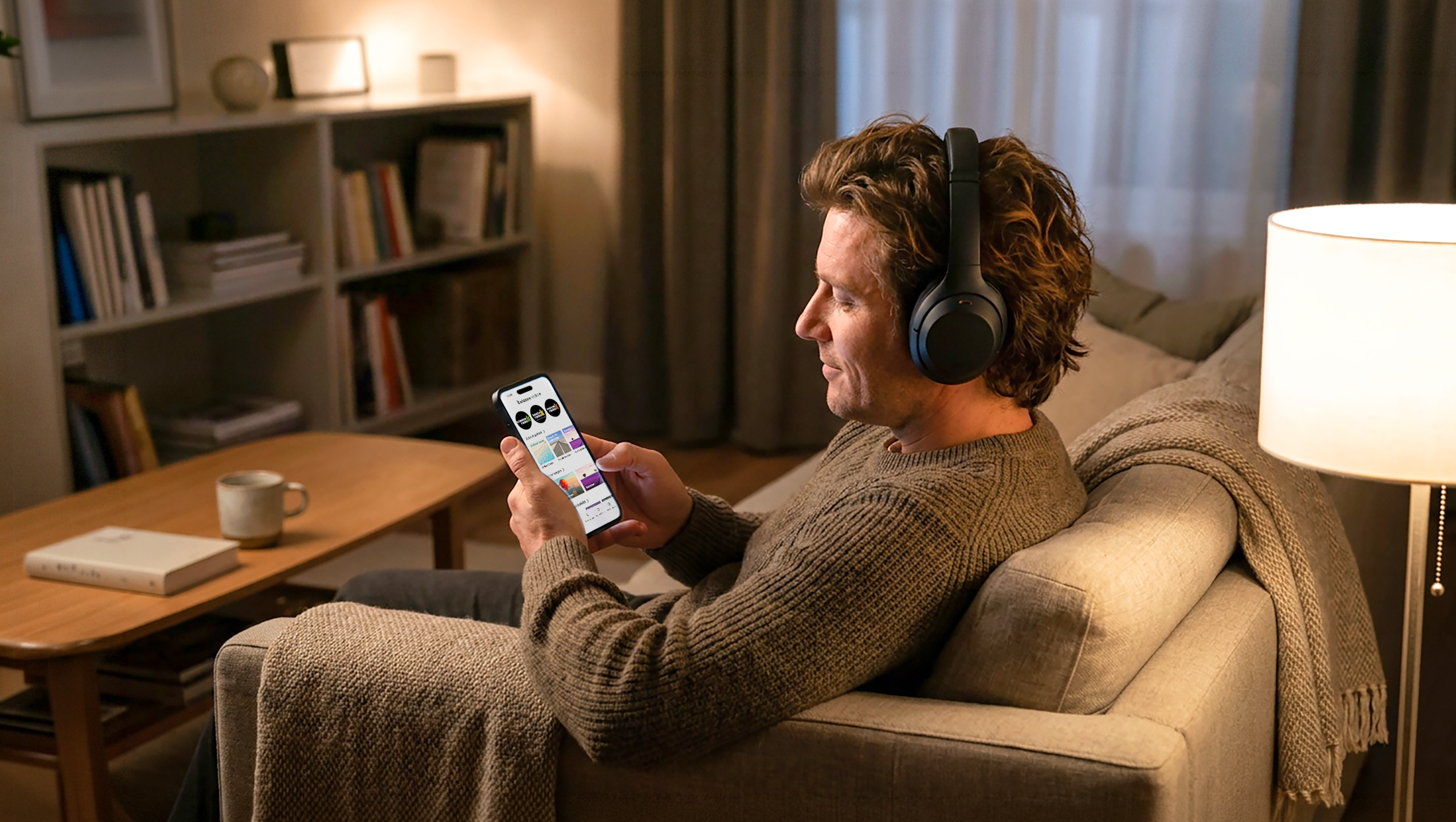 Mann nutzt auf seinem Sofa die Klassik Radio Plus App mit kuratierten Musiksendern.