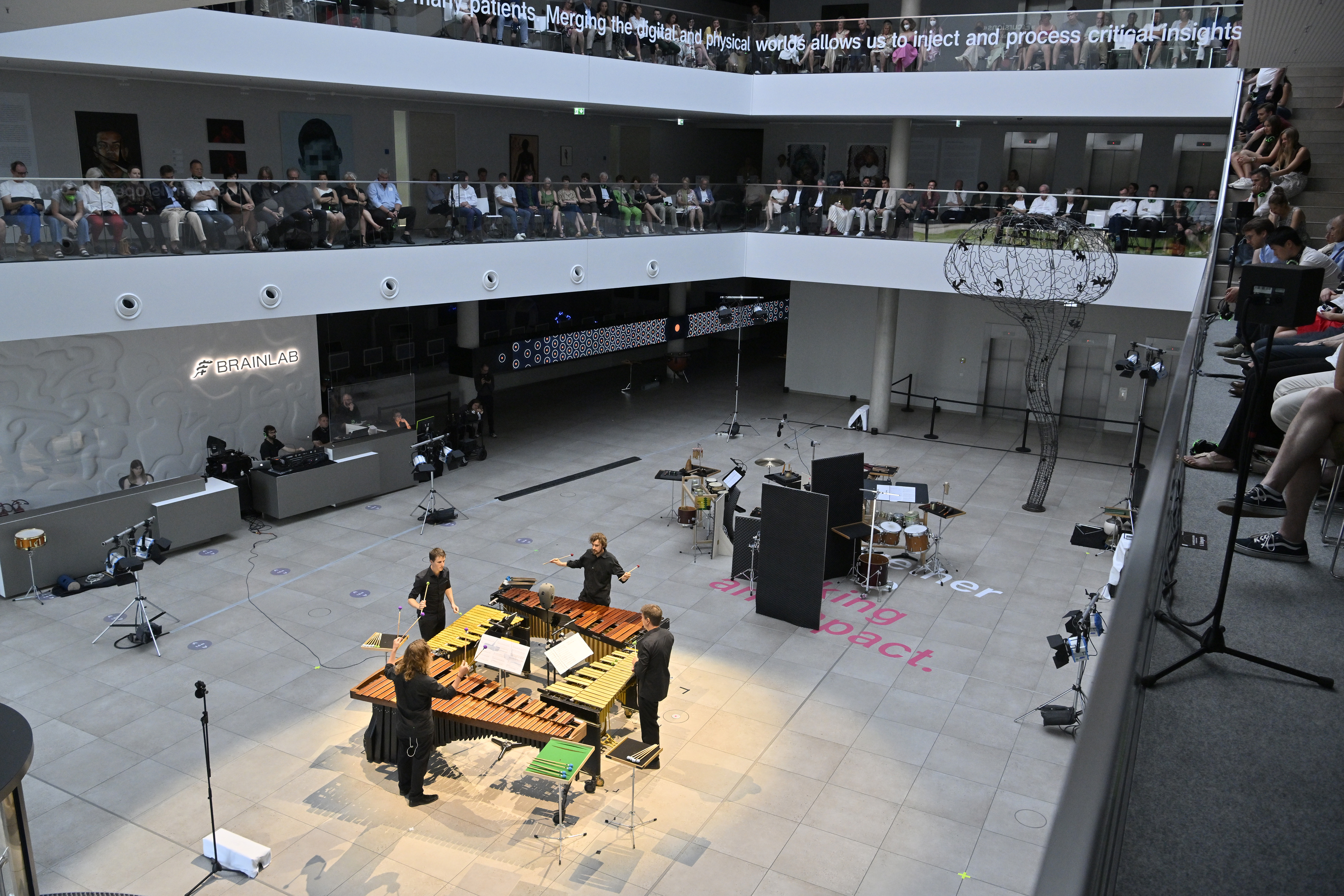 Publikum sitzt auf Balkonen rund um die tiefer liegende Bühne mti Musikern