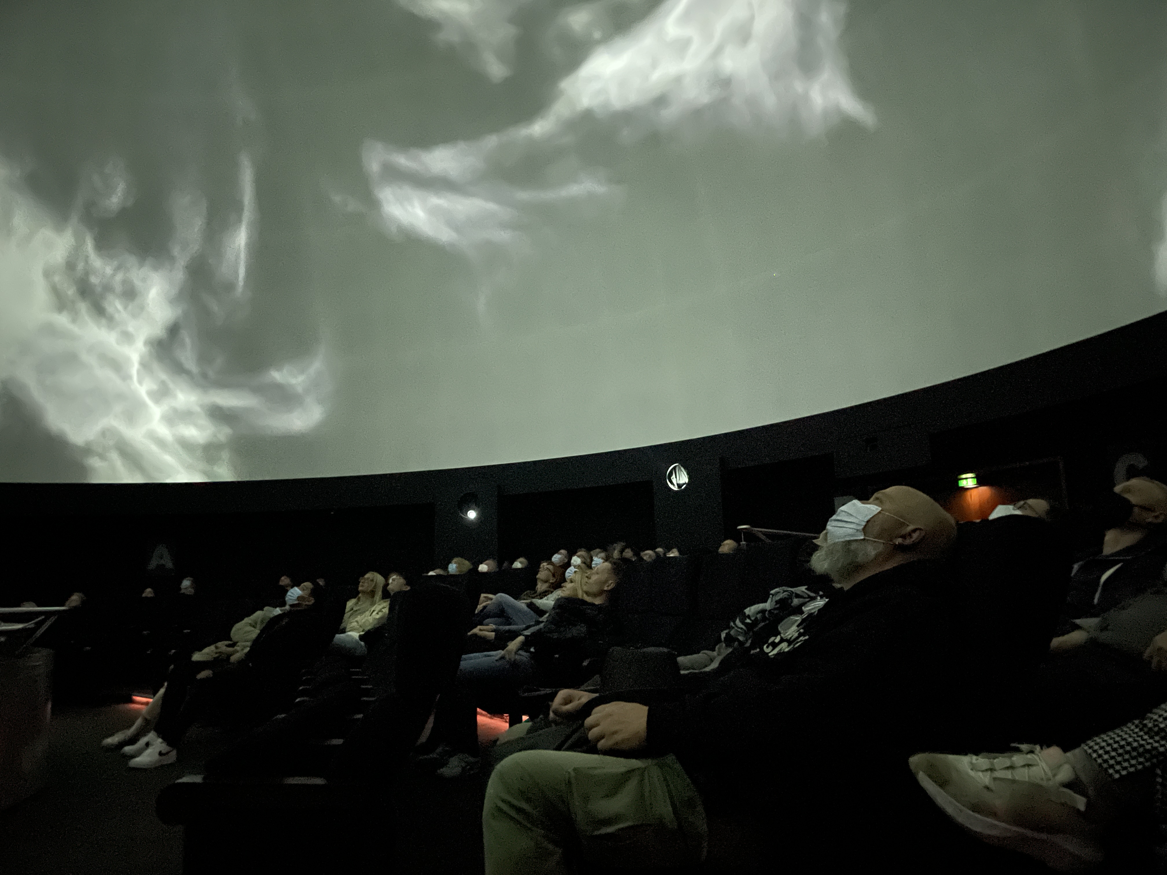 Zuschauer blicken an die Decke des Planetariums in Berlin