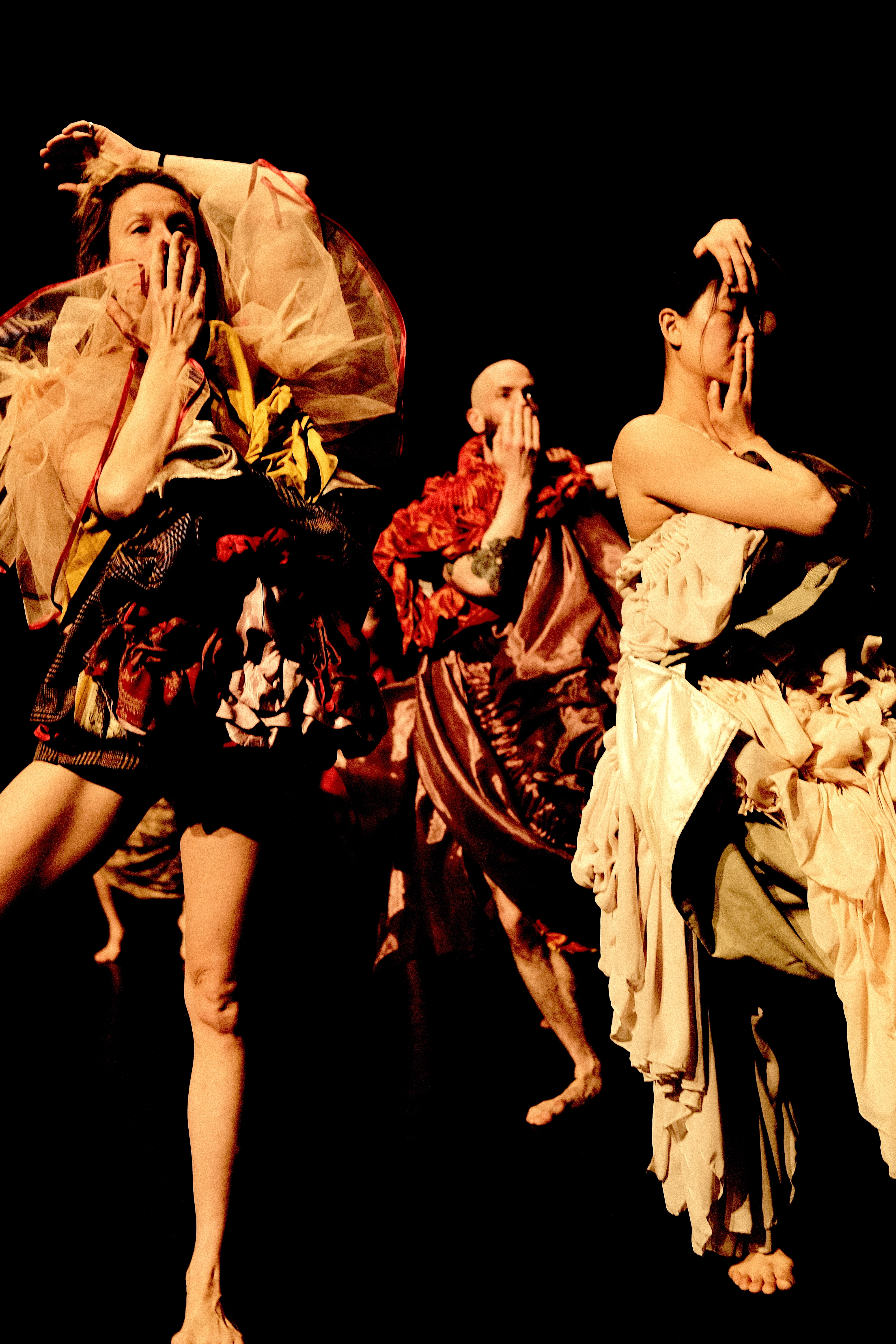 Zwei Tänzerinnen und ein Tänzer bei den Proben, die sich die Hand vor den Mund halten