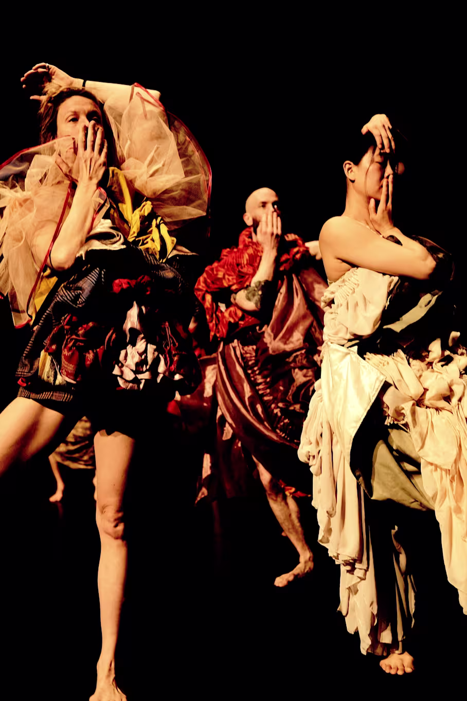 Zwei Tänzerinnen und ein Tänzer bei den Proben, die sich die Hand vor den Mund halten