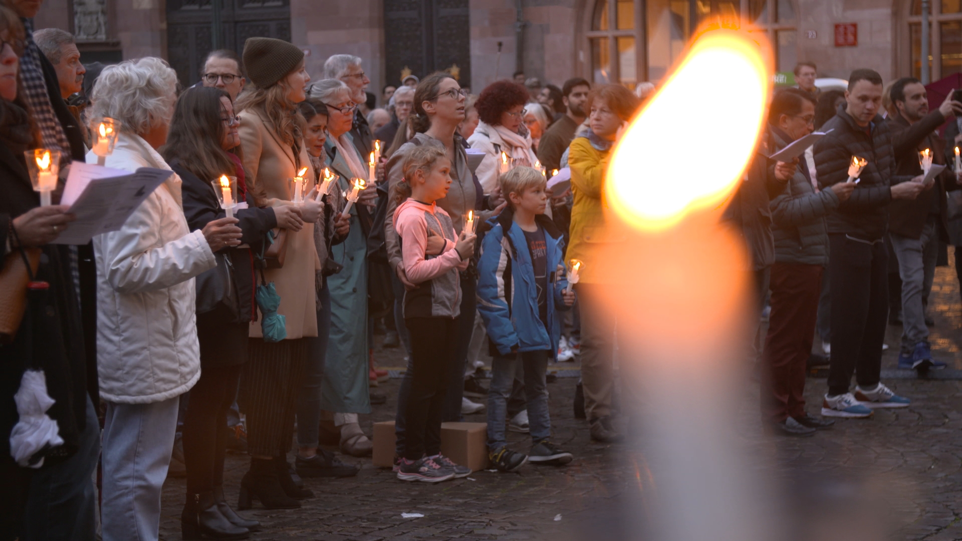 Viele Menschen singen zusammen, mit einer Kerze in der Hand 
