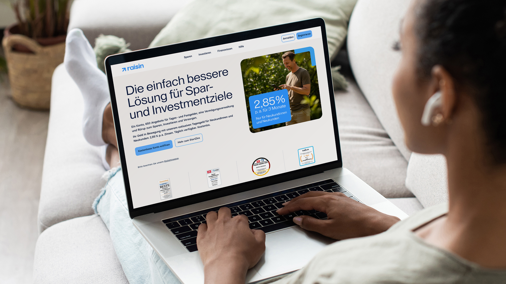 Person sitzt auf Sofa und surft auf Laptop, auf dem eine Webseite zu Spar- und Investmentzielen geöffnet ist