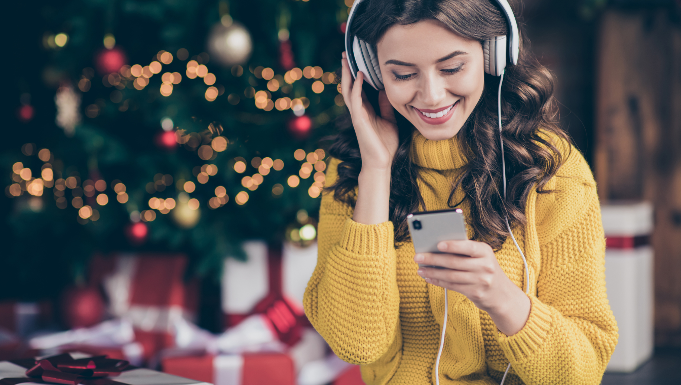 Frau hört Musik vorm Weihnachtsbaum
