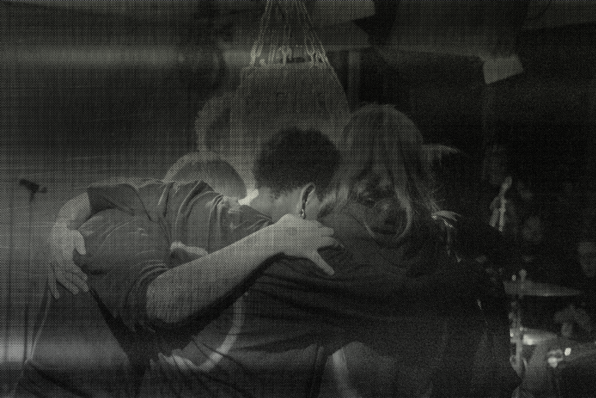 Three performers huddle around a punching bag.