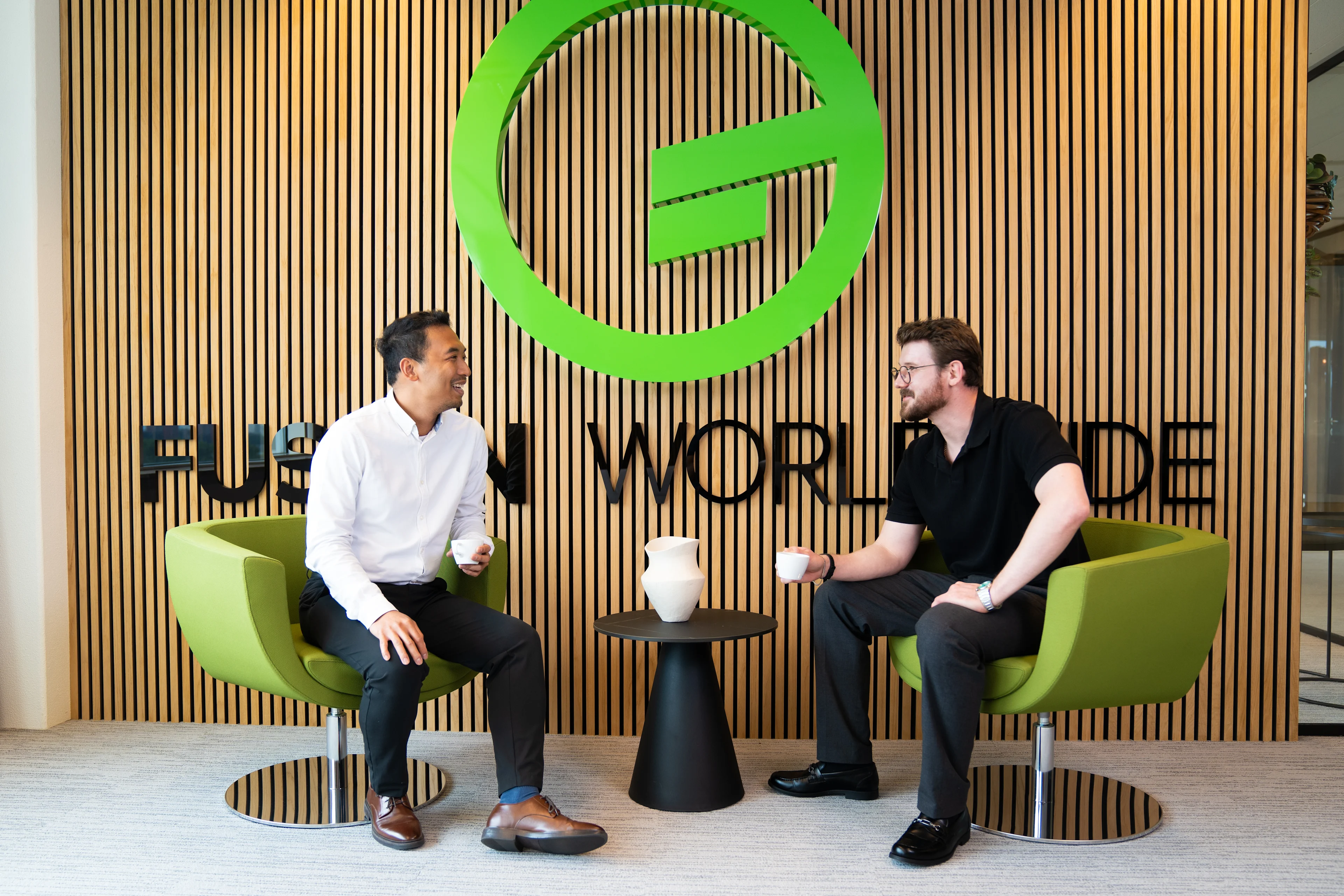 Team meeting and collaborating in a glass office with abstract orange artwork in the background