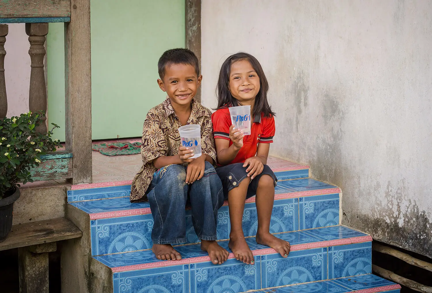 Enfants souriant et tenant un verre d'eau purifiée