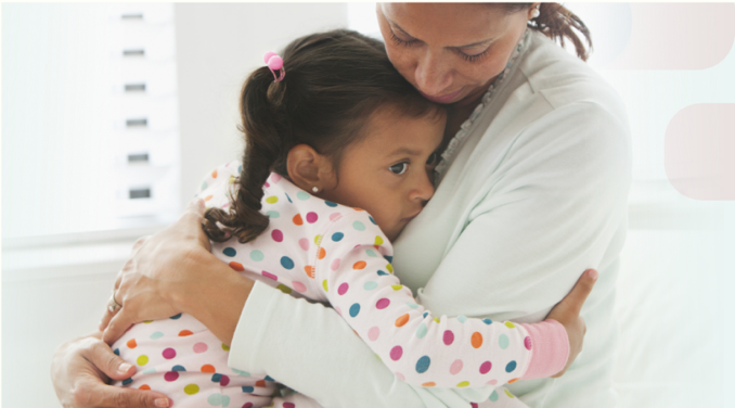 A woman holding her young daughter in a pediatric setting.