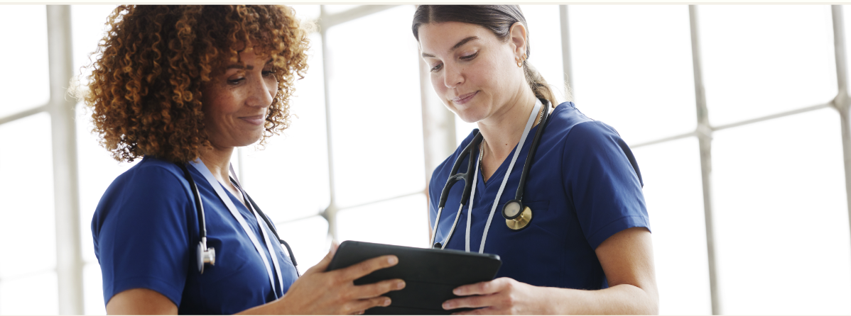 Two medical professionals viewing a tablet device together.