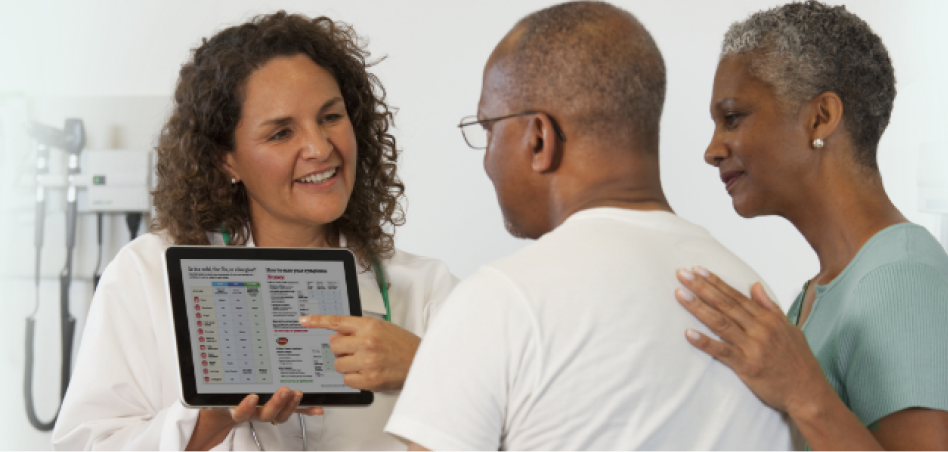 A medical professional showing a TYLENOL® dosage chart to a patient and their caregiver.