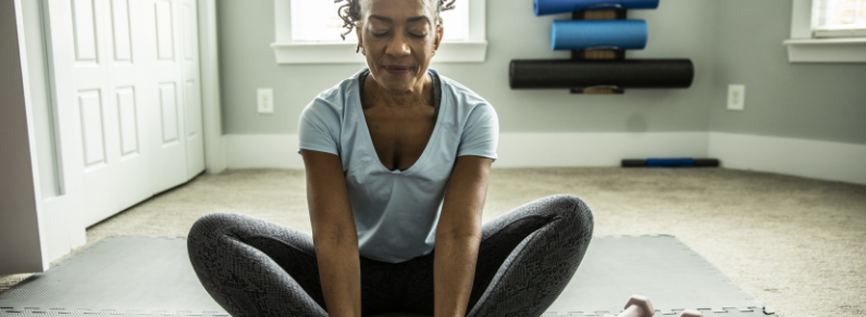 Woman sitting and stretching on a mat.