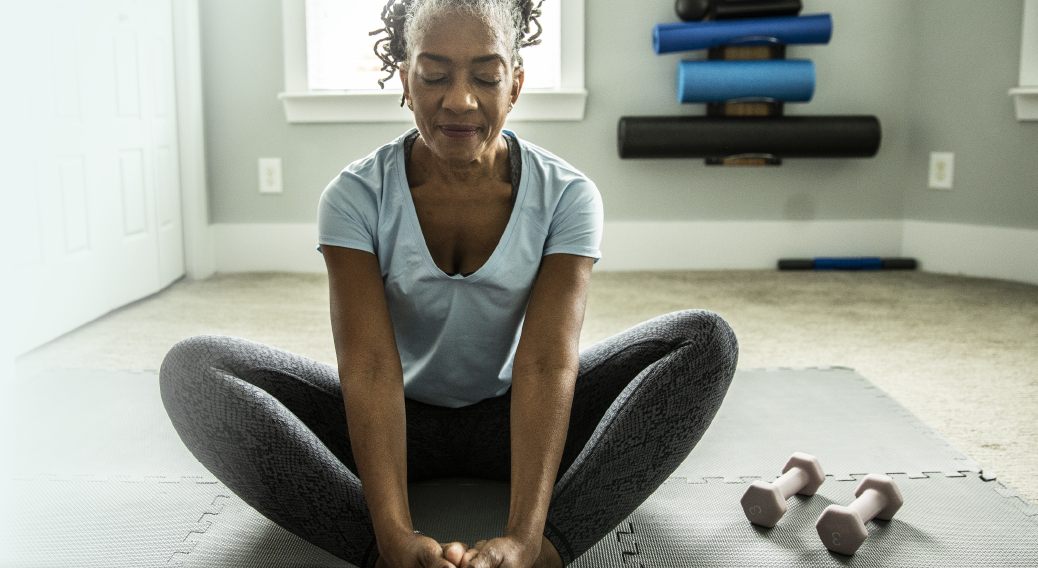 Woman sitting on a mat and stretching.