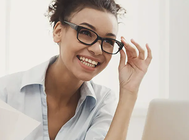Woman with glasses looking at a laptop.