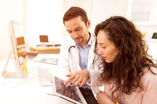 Une femme avec un médecin, le medecin lui montre quelque chose sur une tablette