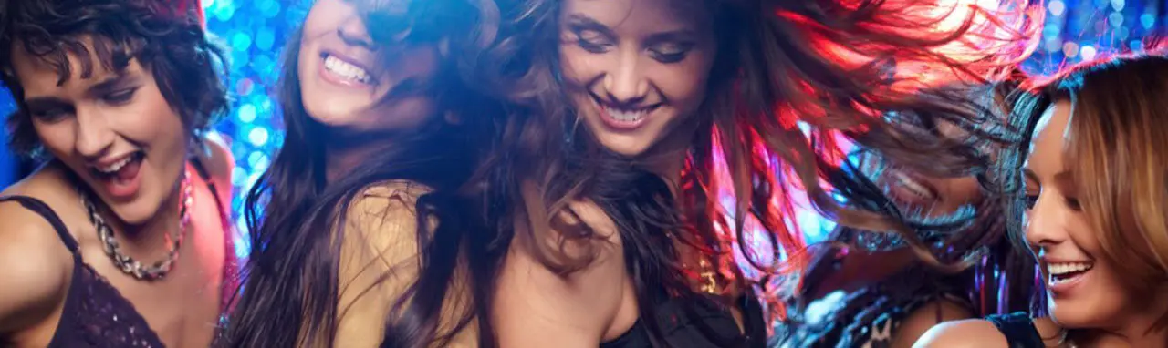 Un groupe de quatre jeunes femmes dansent dans une boite de nuit