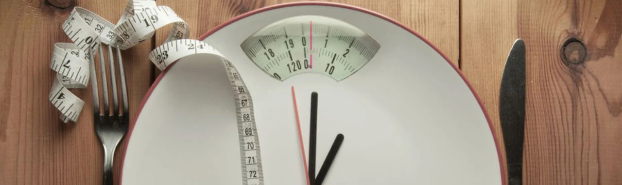 Pèse-personne posé sur une table avec des couverts arrangés autour pour faire la faire ressembler à une assiette