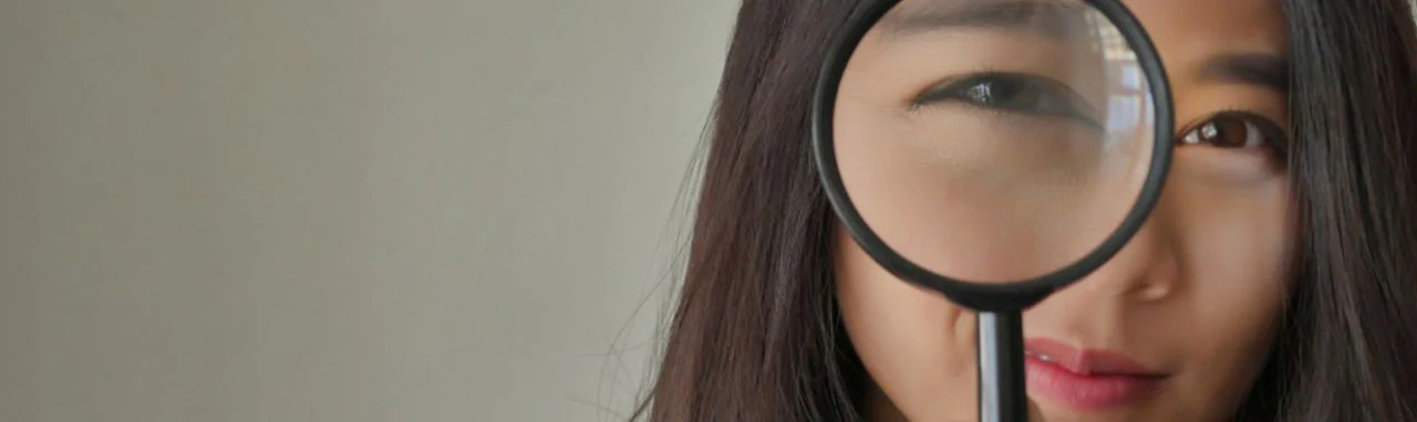 Photo d'une femme tenant une loupe devant son œil droit