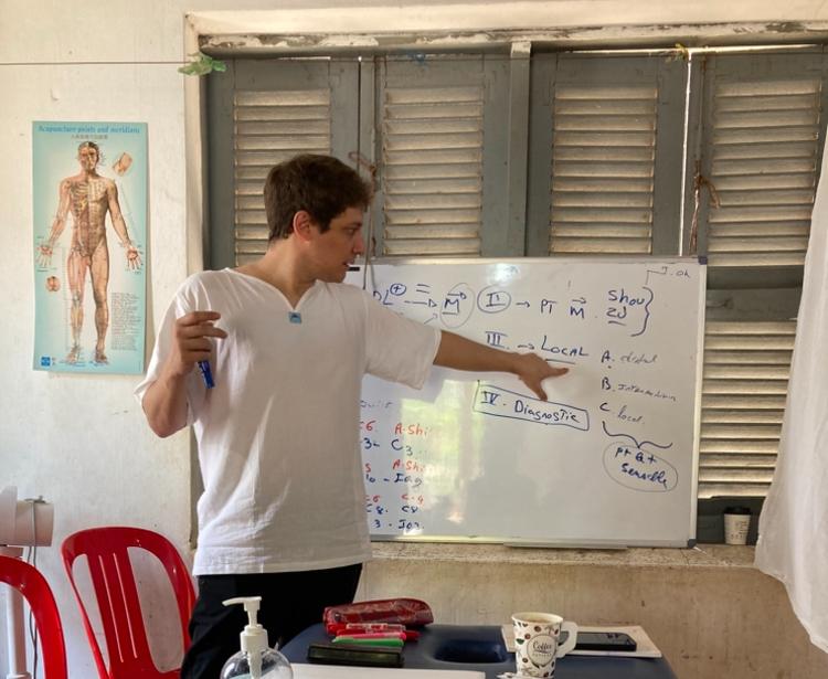 Nicolas Berger devant un tableau donnant un cours sur les points d'acupuncture Tung