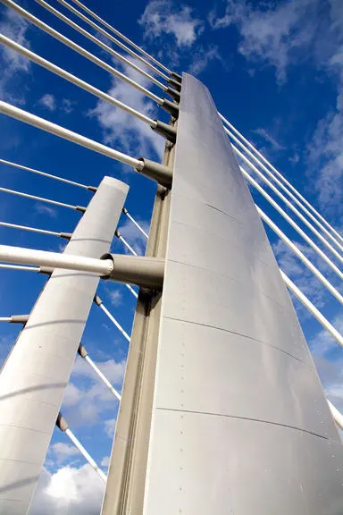 Close-up of the modern Crusell Bridge structure against a blue sky with clouds.