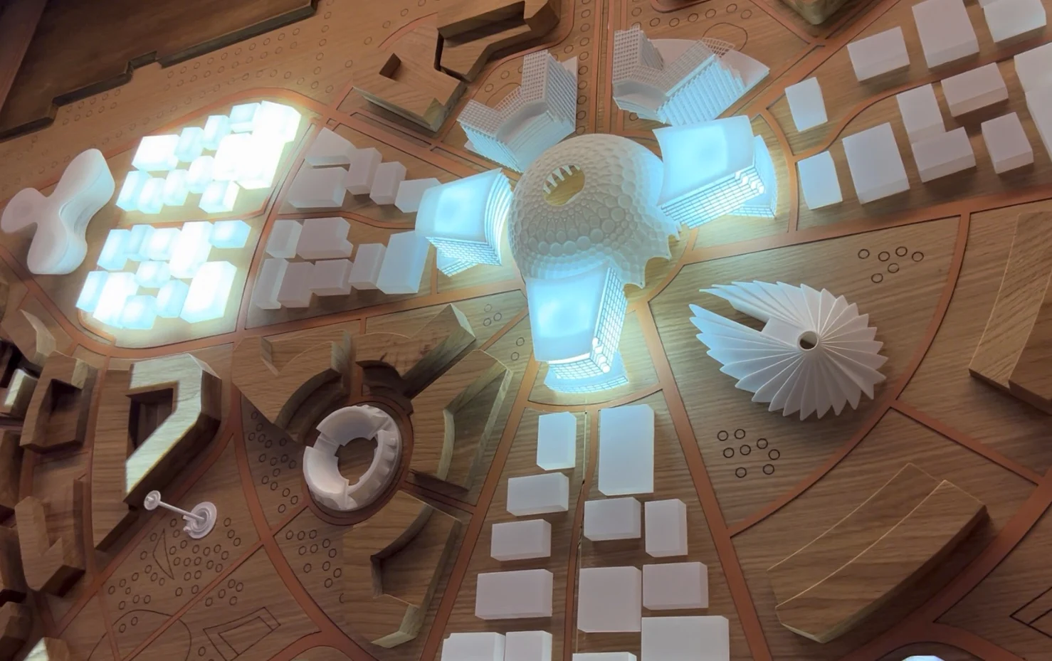 Architectural model of a futuristic city with glowing buildings and a central dome.