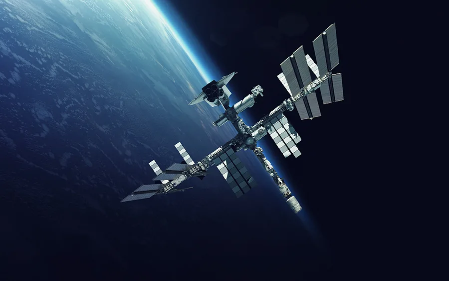 The International Space Station orbits above Earth, with vast solar panels extended.