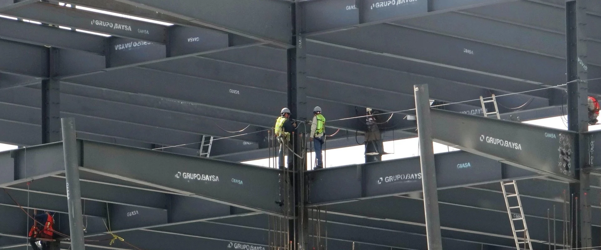 Construction workers are shown working on a steel building framework.