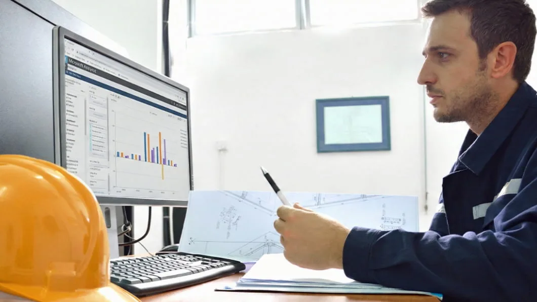 A focused worker in blue coveralls points to Viewpoint Analytics data on a monitor.