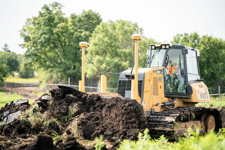 Yellow bulldozer with GPS equipment grading dirt on a construction site.