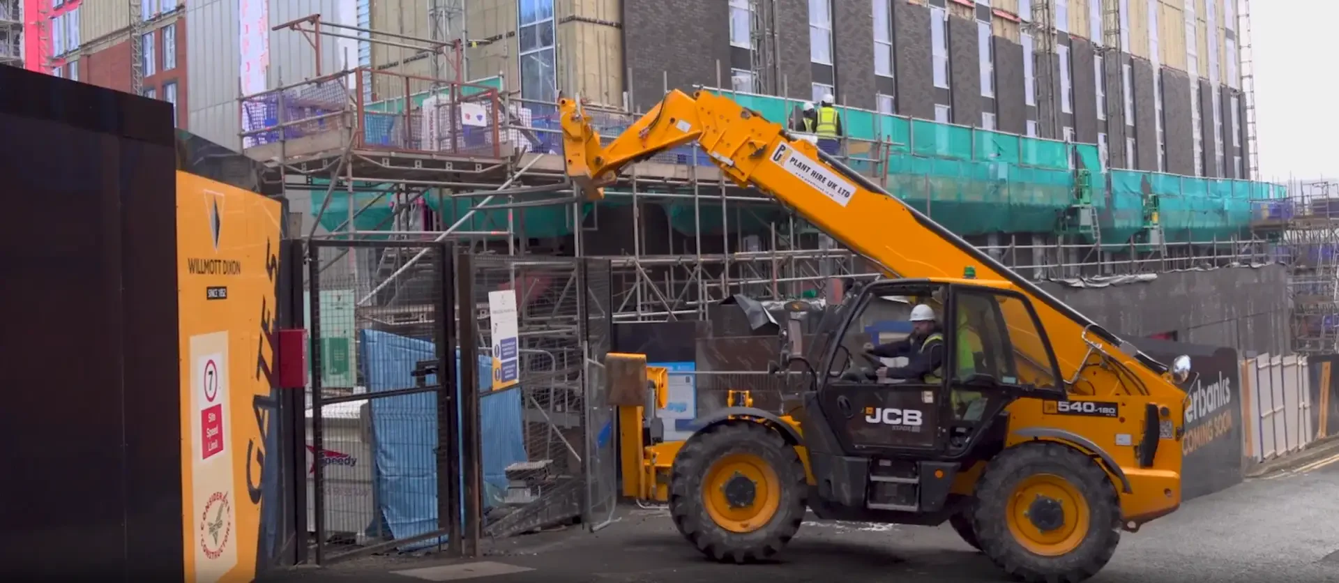 Forklift moving materials at a Rochdale Riverside Project site with scaffolding.