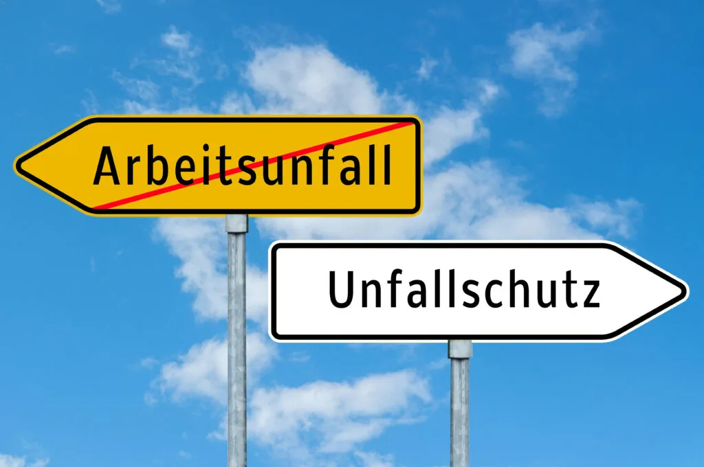 German signs: one indicating Arbeitsunfall (work accident) with a line through it, the other Unfallschutz (accident protection).