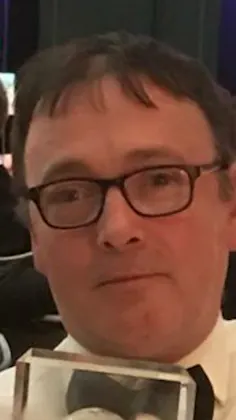 Man in glasses holding an award.