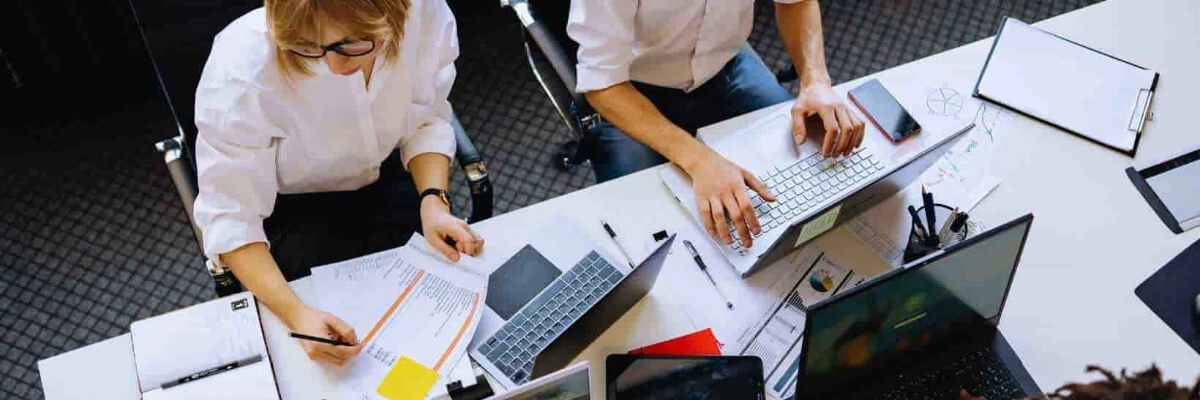 Group of people working together at a table with laptops and documents