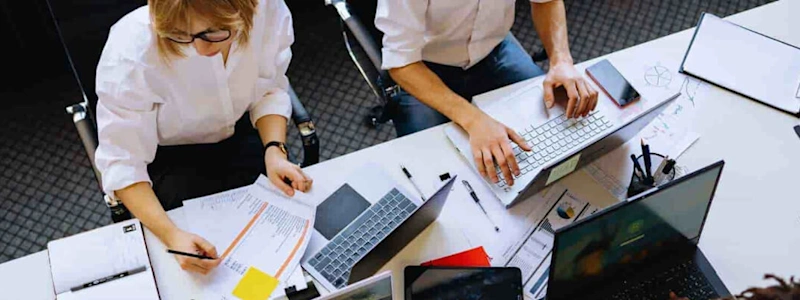 Group of people working together at a table with laptops and documents