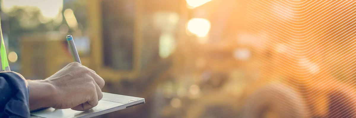 Worker in safety vest writing on a tablet at a construction site