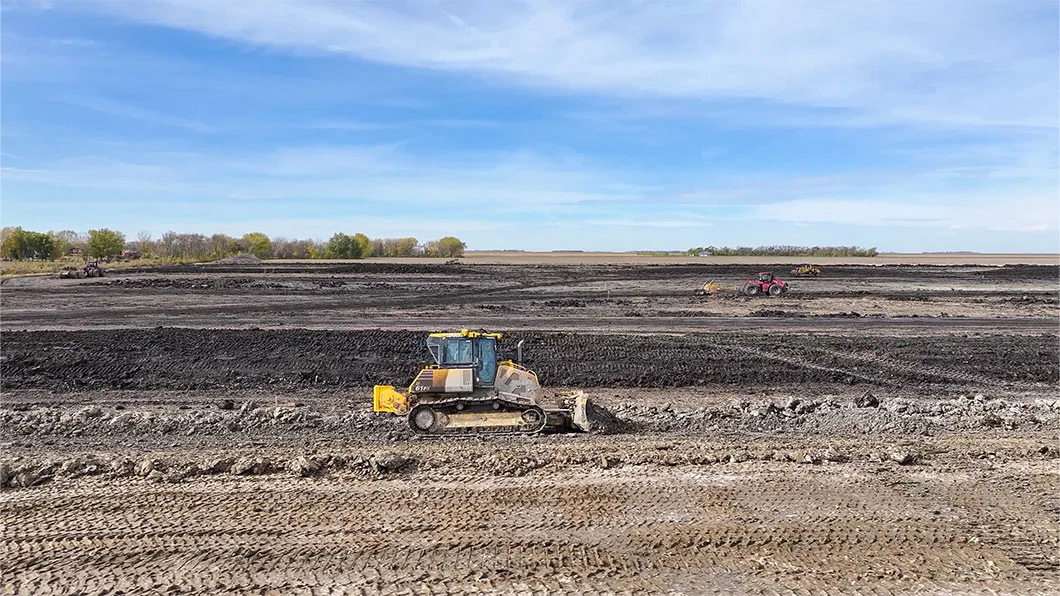 A bulldozer with a scraper in a large agricultural field