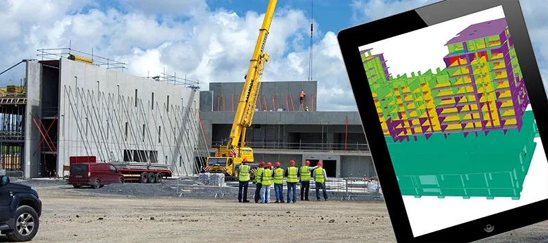 A group of construction workers in hard hats and safty vests stand facing a building under construction. A tablet displays a 3D model of the building.