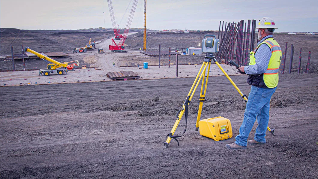 A man in safety gear on a construction site working with a Trimble total station